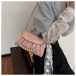 Détail du sac nuage rose montrant le cuir verni plissé et la chaîne en perles