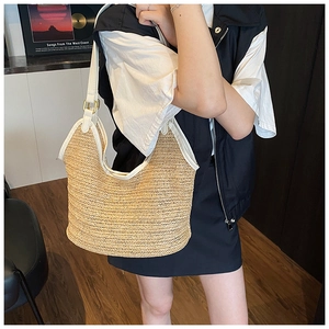 Close-up of woven straw tote bag with white leather straps and gold metal buckles