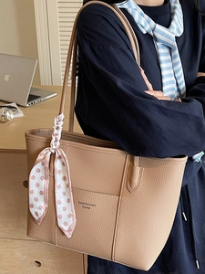 Brown leather tote bag with silk scarf handle and printed lettering for daily commute