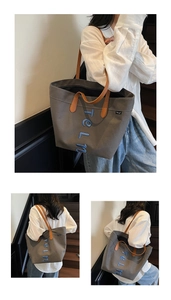 Close-up of embroidered blue letters and brown leather handles on gray canvas tote bag