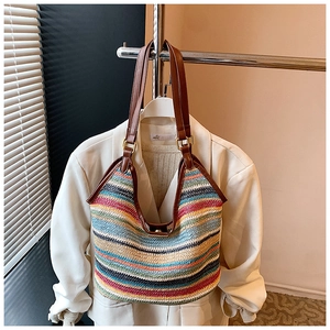 Detail of multi-color striped woven straw bag with premium leather handles and metal hardware