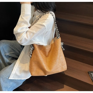Detail of hand-woven straw tote bag with elegant black and white striped ribbon handle