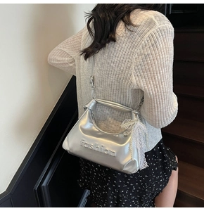 Detail view of silver mirror handbag with fashion embossing and white lace bow