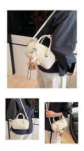 Detail of a minimalist beige shoulder bag featuring a cute teddy bear charm and metal rings