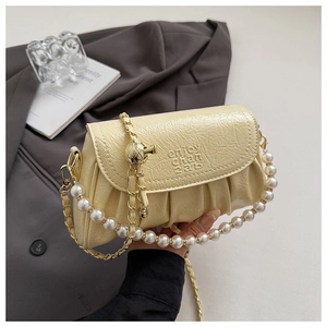 Détail du sac nuage crème avec poignée en perles et texture de chaîne dorée