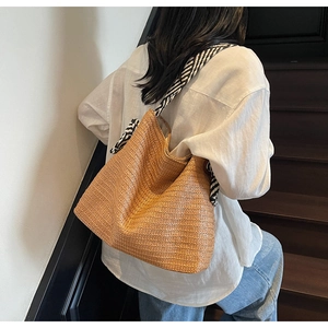 Close-up of woven straw tote bag with stylish zebra pattern fabric shoulder strap