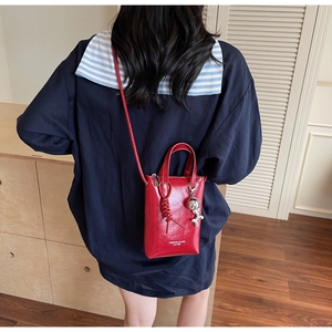 Dettaglio borsa porta cellulare in pelle rossa con ciondolo astronauta e testo moda