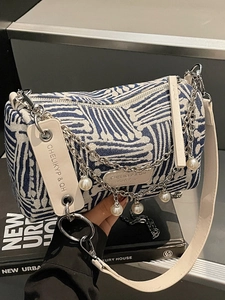 Blue and white woven cylinder tote bag with wide leather strap and pearl chain detail