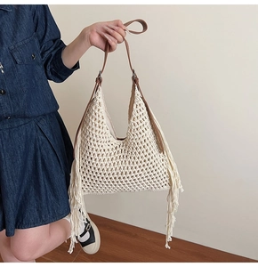Detail of bohemian hollow hand-woven beach tote bag with long fringe and leather handles