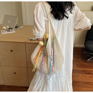 Detail of crochet tote bag with colorful tassels and soft cotton woven pattern