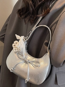 Sac hobo argenté en forme de croissant avec nœuds et breloque cœur perle sur modèle