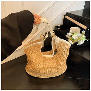 Detail of hand-woven straw bag with white leather trim and elegant gold hardware