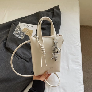 Dettaglio borsa porta cellulare bianco crema in pelle PU con ciondolo a forma di cane