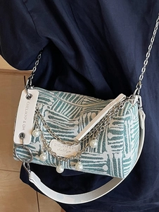 Striped green and white shoulder bag with pearl chain and metallic strap worn over the shoulder