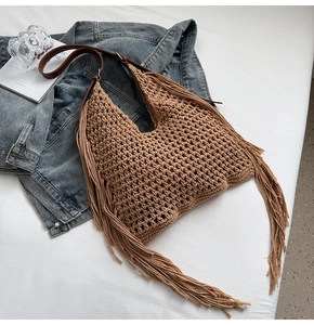 Detailed close-up of brown crochet tote bag with bohemian long fringe and leather strap