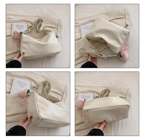 Detail view of cream PU leather tote bag with wide strap and peach plush pendant