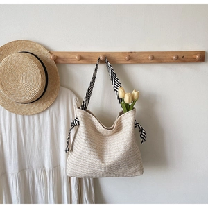 Detail of woven straw tote bag with black and white striped handles and decorative tulips