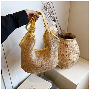 Detail showing handwoven texture and yellow leather handle of this bohemian straw bag