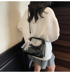 Detail of glossy black oil wax leather handbag featuring fashion embossed text and pearls