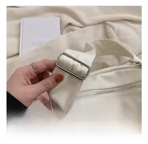 Detailed shot of white PU leather tote featuring adjustable wide strap and pink plush charm