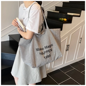 Detail of striped canvas tote bag with Make Magic HAPPEN print worn by model on stairs