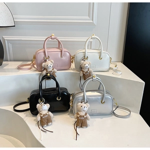 Detail view of four small square crossbody bags in pink, white, black and silver colors