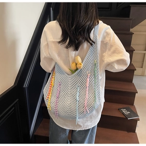 Detail of light blue crochet tote bag with colorful tassels and hollow mesh design