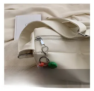 Detail of cream PU leather shoulder bag with silver hardware and peach plush charm
