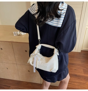 Detail of white crescent leather handbag with pearl lace bow charm and fashion embossing