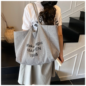 Detail of large black and white striped canvas tote bag with Make Magic Happen print
