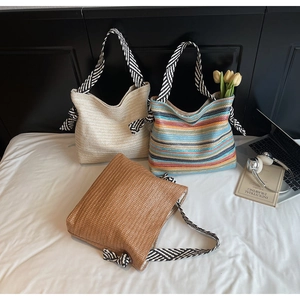 Detailed view of woven straw tote bags with stylish black and white twill knotted handles