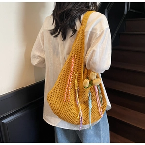 Detail of yellow crochet tote bag with colorful tassels and a tulip accent