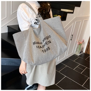 Detail of large black and white striped canvas tote bag with Make Magic Happen slogan