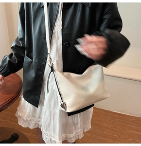 Detailed view of white leather shoulder bag with a stylish metal heart charm accessory