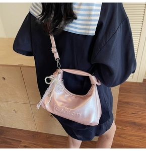 Pink glossy oil wax leather handbag with fashion logo and pearl bow detail on model