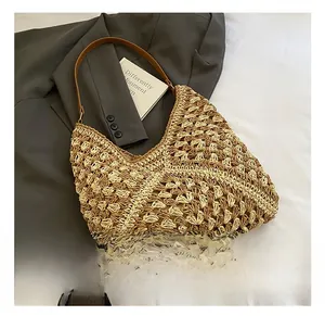 Detailed close-up of woven diamond pattern on beige straw tote bag with brown strap