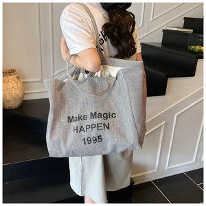 Detail of canvas tote bag showing Make Magic HAPPEN 1995 print and black stripes