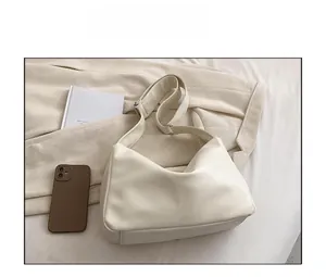 Detail of creamy white PU leather tote bag with wide adjustable strap on fabric