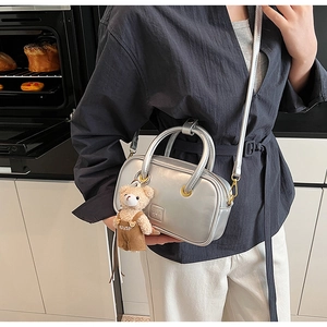 Close-up of silver Boston bag with a cute teddy bear charm in a lifestyle kitchen setting