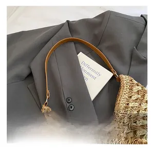 Detail of woven tote bag with brown leather handle on a stylish blazer background