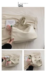 Detail view of pearl white crossbody bag with smooth texture and cute plush strawberry charm