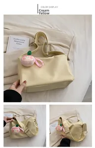 Detail of creamy yellow tote bag with pink peach charm and wide adjustable strap