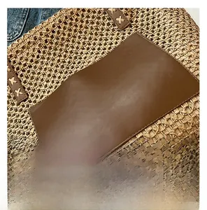 Detailed macro view of woven straw beach tote with premium brown leather stitching details
