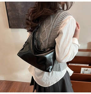 Detail of black patent leather hobo bag showing glossy texture and shoulder strap fit