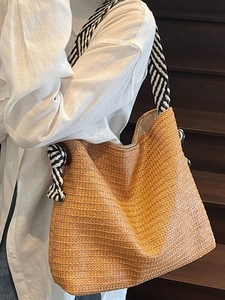 Large straw tote bag with black and white striped straps for summer beach vacations