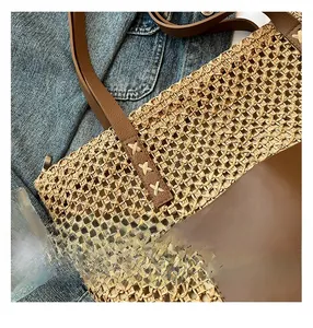 Detail showing high-quality straw weave and brown leather handle with reinforced stitching