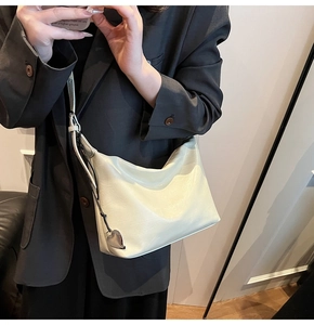 Detail of a creamy white soft hobo bag featuring a silver heart charm and leather texture