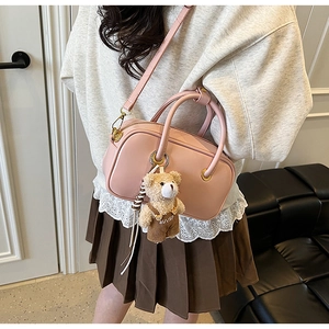 Detail of pink cylindrical shoulder bag with a cute bear pendant and golden zipper