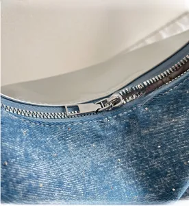 Gros plan sur la fermeture éclair argentée et les strass sur le sac en denim bleu