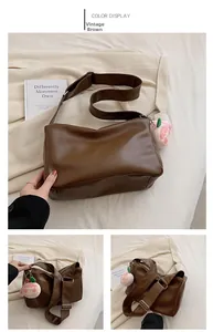 Detail of vintage brown leather tote bag with wide strap and plush peach charm